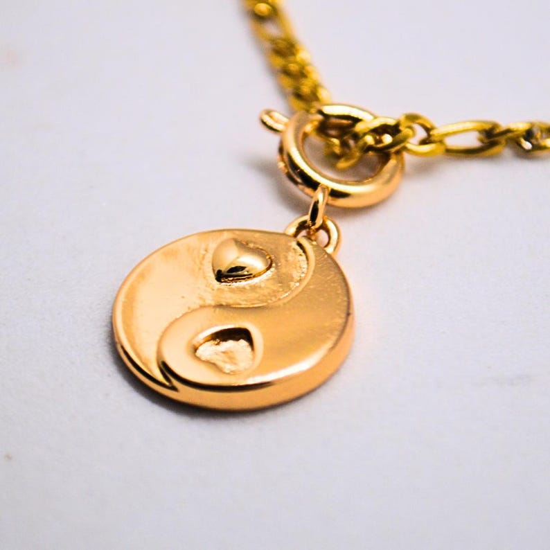 Gold chain necklace with a heart yin yang charm