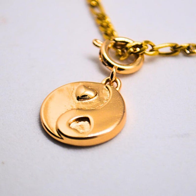 Gold chain necklace with a heart yin yang charm