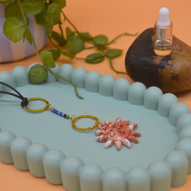 Sun pendant on a black cord on a tray